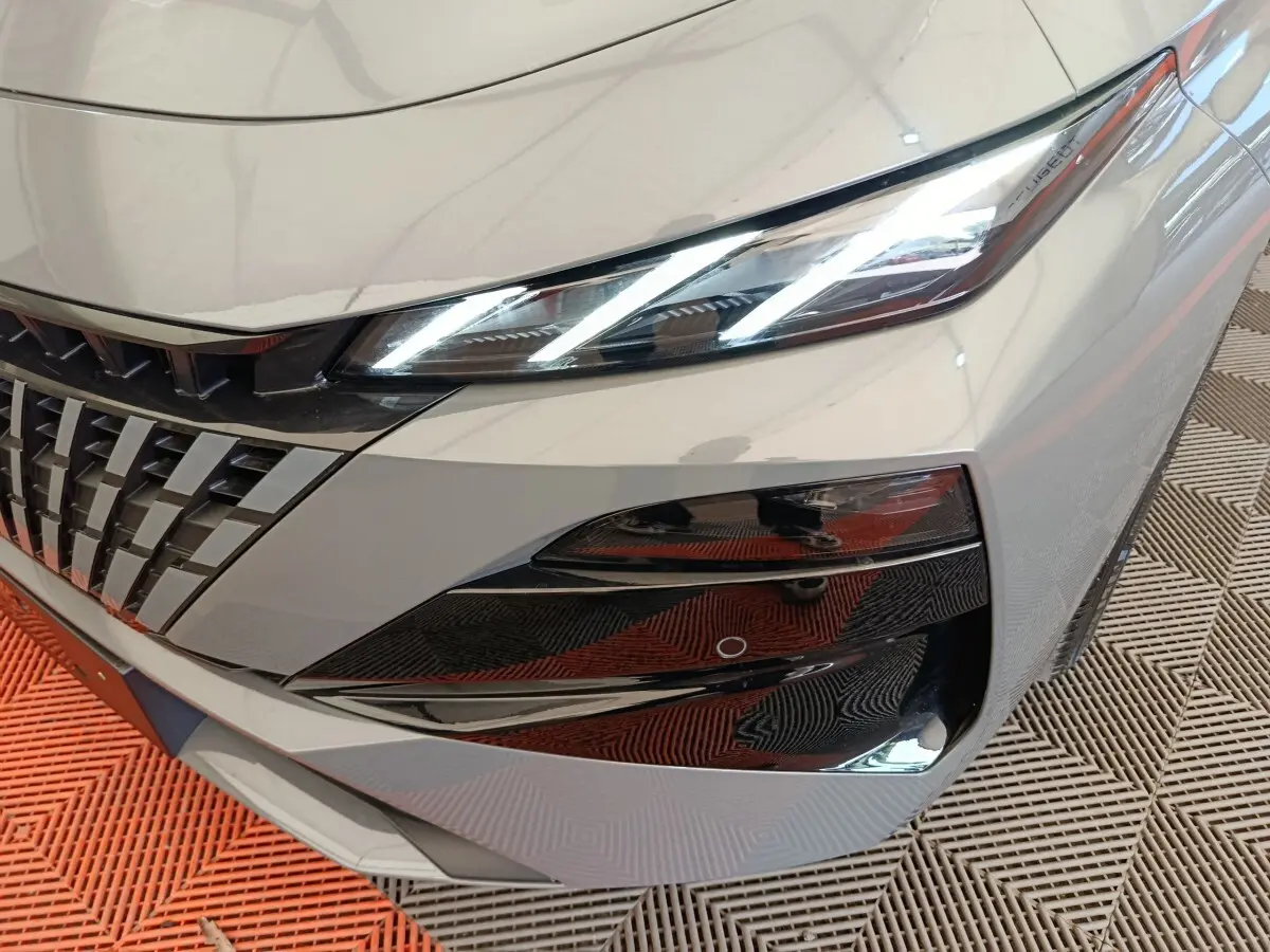 Gros plan sur l'avant droit gris foncé du Peugeot 308 2026, mettant en valeur les phares LED et la calandre distinctive.