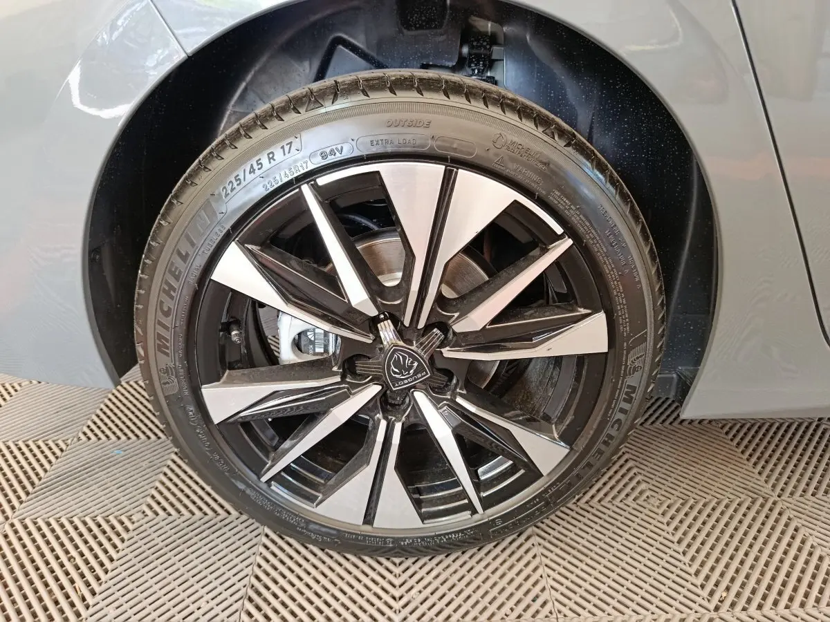 Gros plan sur la roue avant droite de la Peugeot 308 gris foncé, avec jante alliage noire et argentée au design moderne.