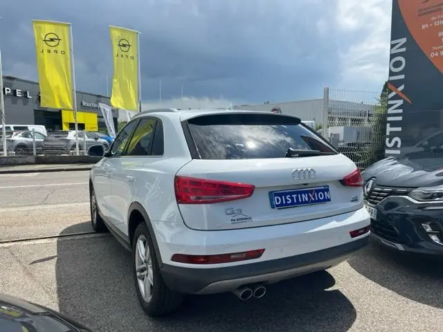 Audi Q3 blanc vue 3/4 arrière droit, version 2.0 TDI Ambition Luxe, avec double sortie d'échappement visible.