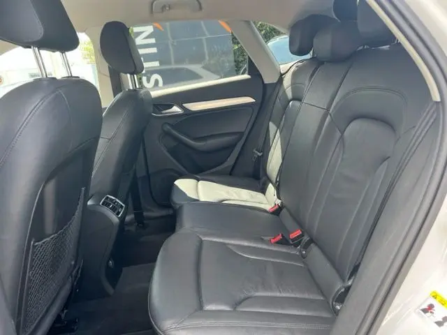 Vue intérieure arrière côté droit de l'Audi Q3 blanc 2015, sièges en cuir noir et appuie-têtes réglables.