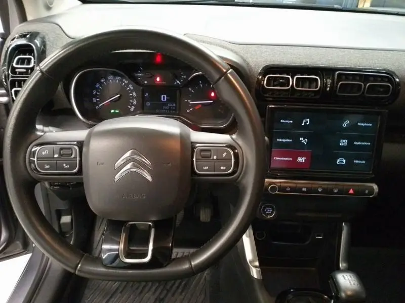 Vue rapprochée du volant et du tableau de bord noir du Citroën C3 Aircross gris avec écran tactile et commandes au volant.