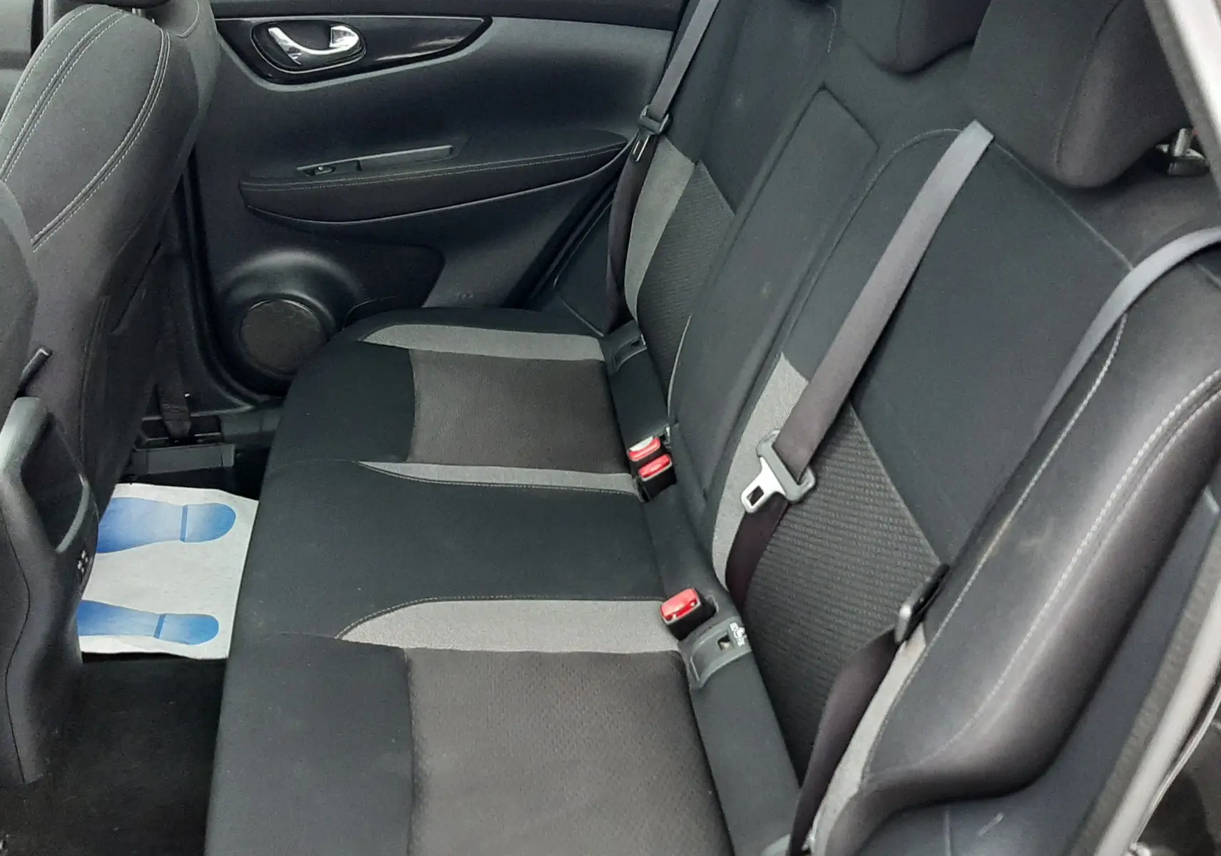 Vue intérieure du siège arrière côté droit du Nissan Qashqai noir 2020, montrant les ceintures de sécurité et la sellerie tissu gris et noir.