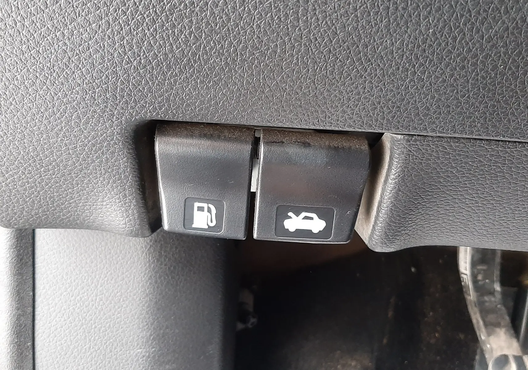 Gros plan sur les commandes d'ouverture de trappe à carburant et de capot, intérieur noir du Nissan Qashqai 2020.