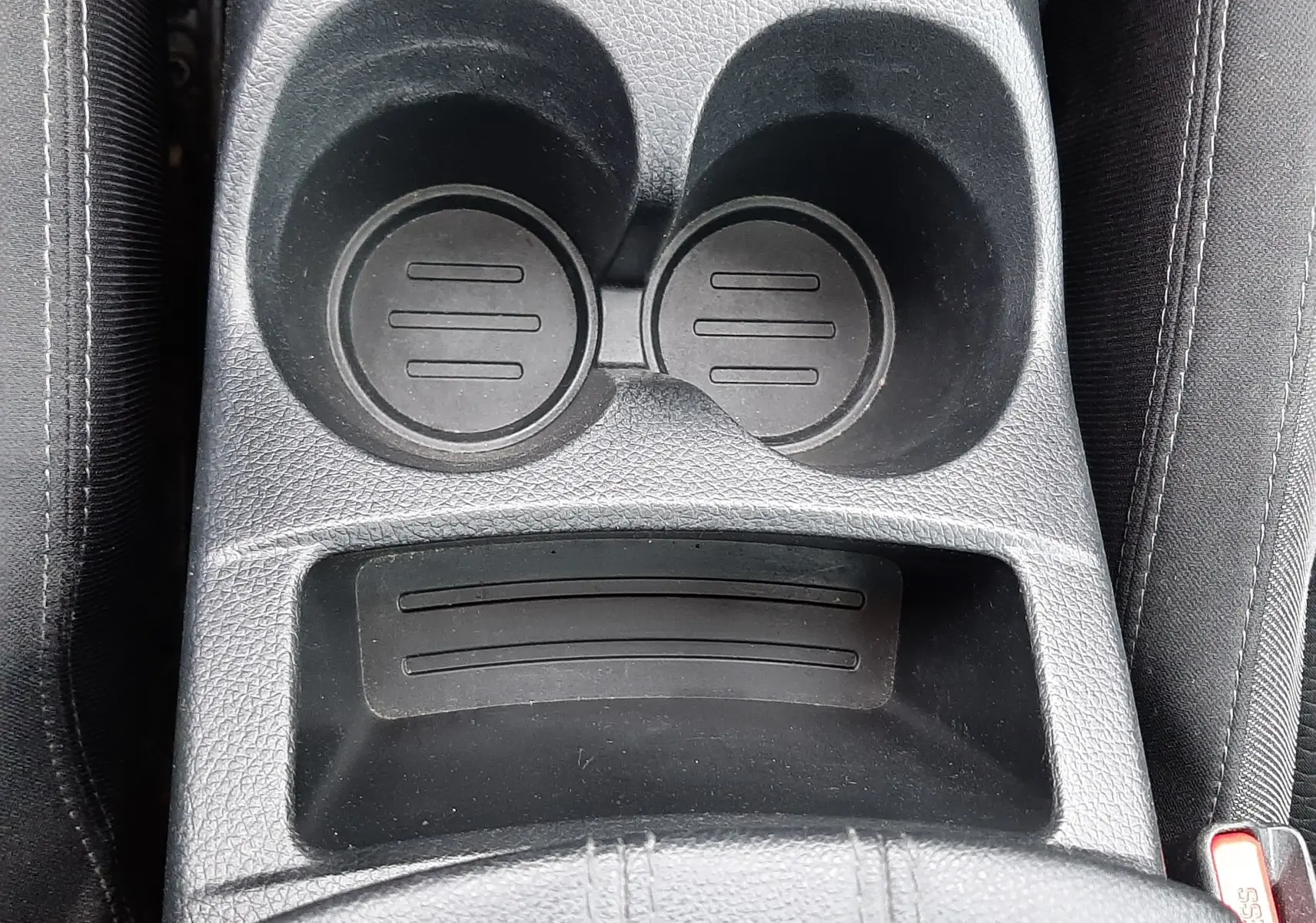 Vue plongeante sur le porte-gobelets noir et la console centrale en tissu gris foncé du Nissan Qashqai DCI 115 N-Connecta 2020.