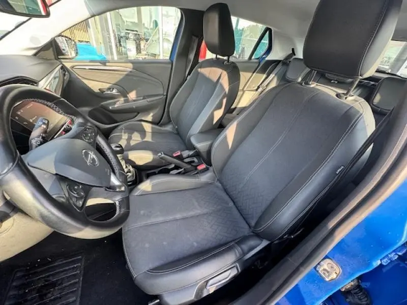 Intérieur avant de l'Opel Corsa bleu voltaïque, sièges noirs et volant cuir multifonction côté conducteur visible.