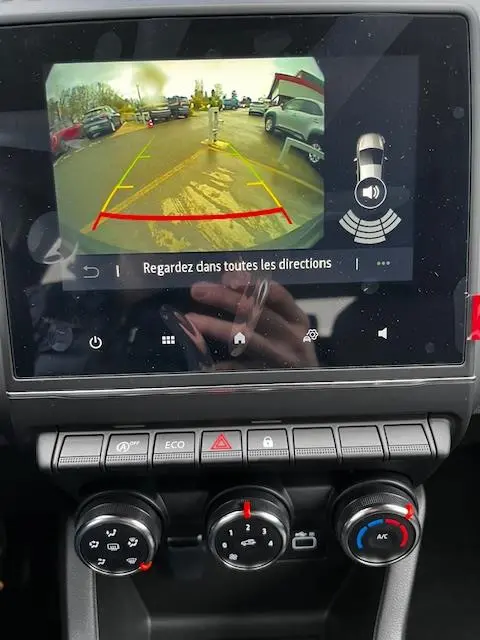 Écran tactile central montrant la caméra de recul d’une Renault Clio noire avec commandes climatisation en dessous.