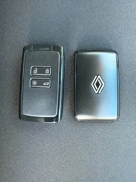 Vue rapprochée de deux clés noires Renault, l'une avec boutons de verrouillage et l'autre avec logo chromé sur fond sombre.