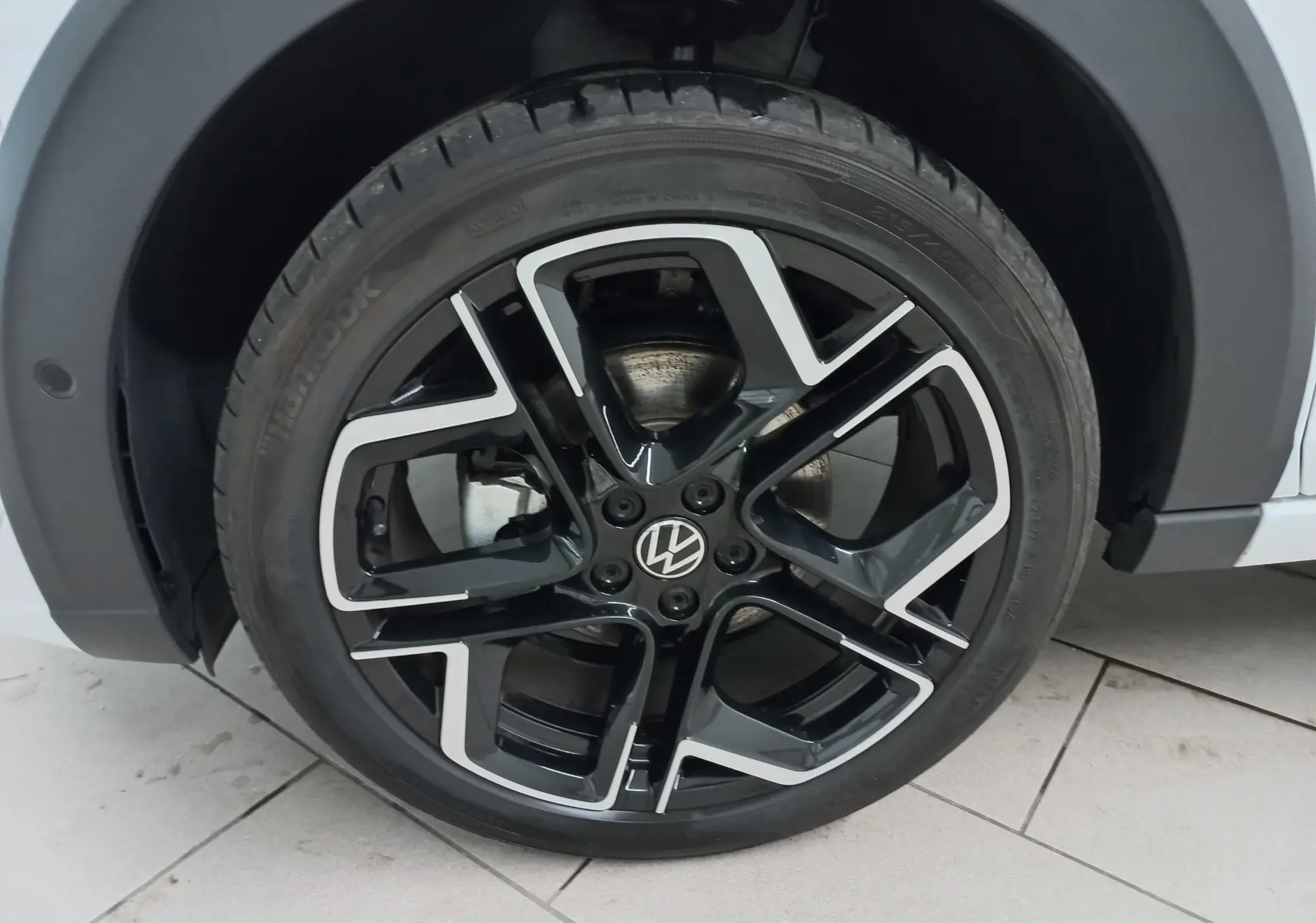 Gros plan sur la roue avant droite du Volkswagen Taigo blanc pur 2025 avec jante alliage noir et argent R-Line.