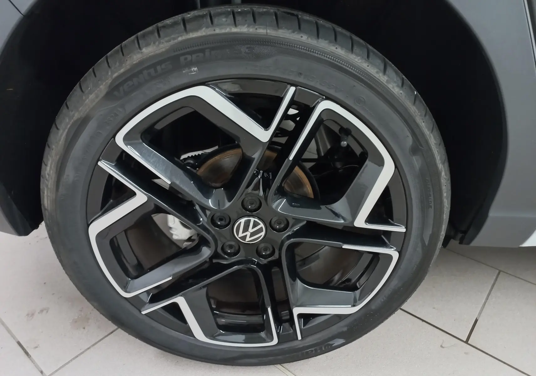 Gros plan sur la jante noire et argentée du Volkswagen Taigo 1.5 TSI 150 DSG7 R-Line 2025, avec logo VW central.