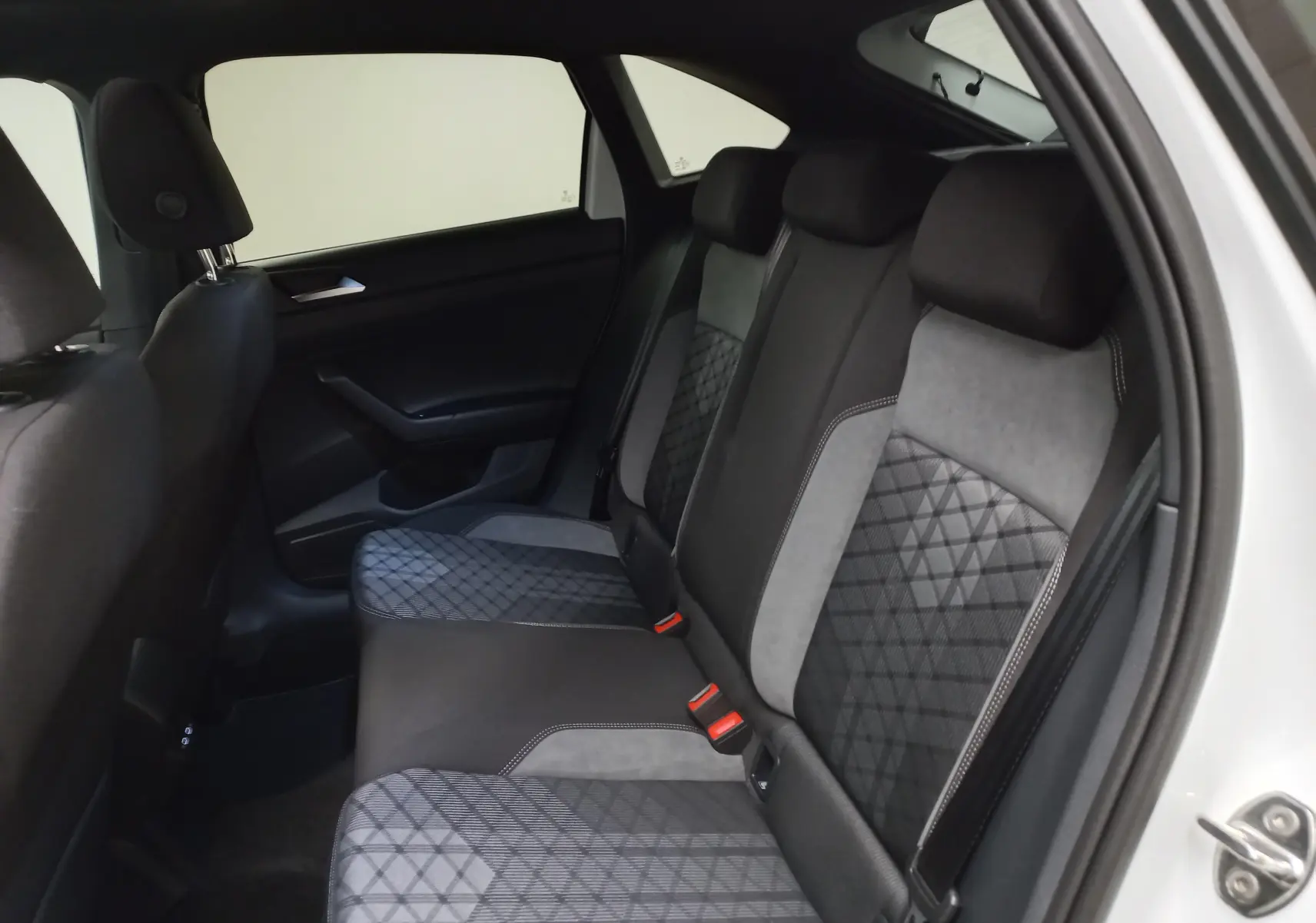 Vue intérieure côté droit des sièges arrière du Volkswagen Taigo blanc pur 2025, avec sellerie noire et grise à motifs géométriques.