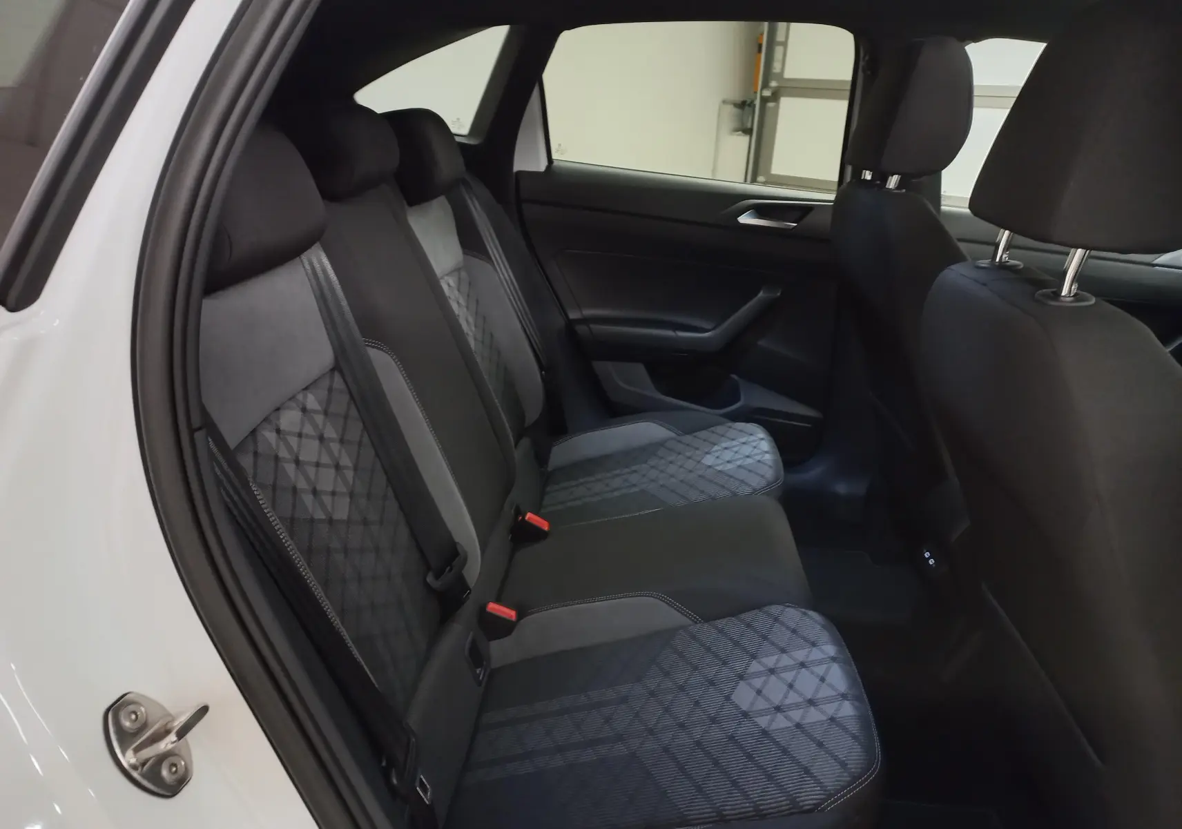 Vue intérieure côté gauche des sièges arrière en tissu gris et noir du Volkswagen Taigo blanc pur 2025 R-Line.