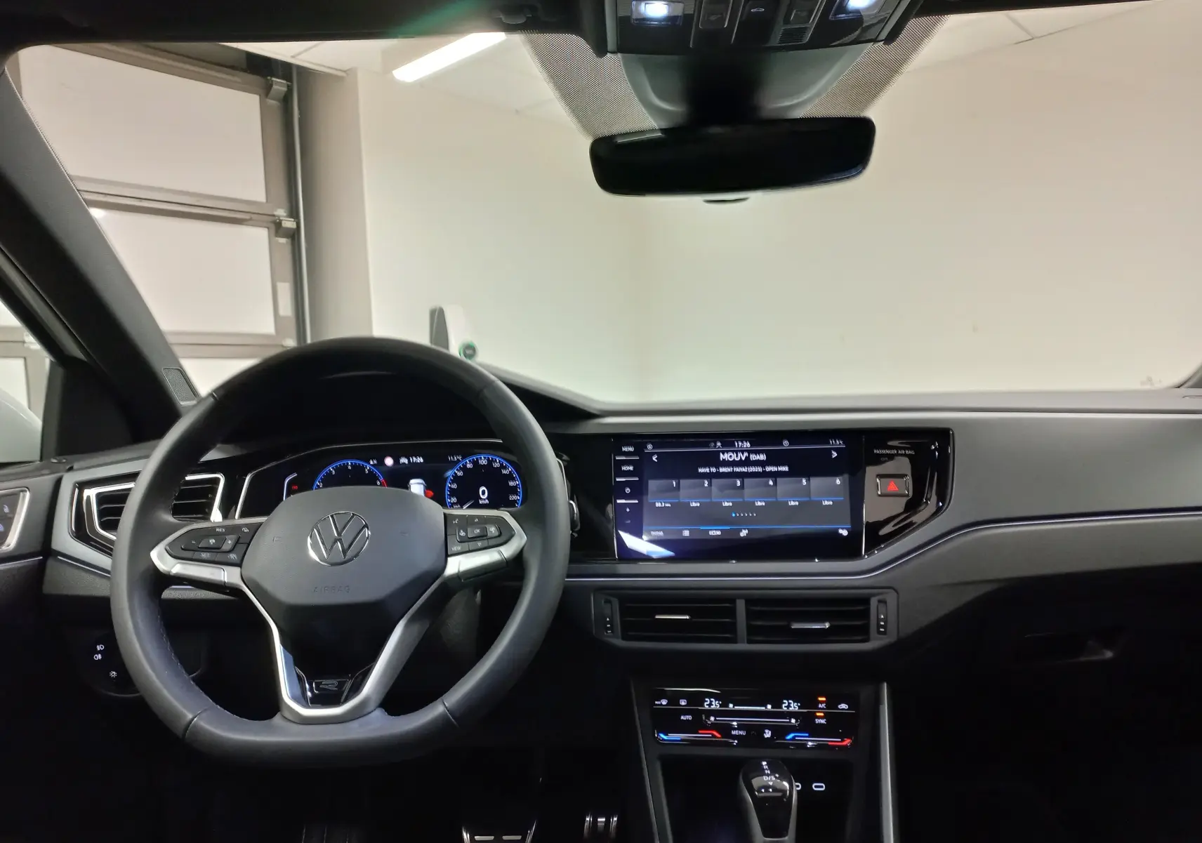 Vue intérieure du tableau de bord du Volkswagen Taigo 2025, avec volant multifonction et écran tactile central allumé.