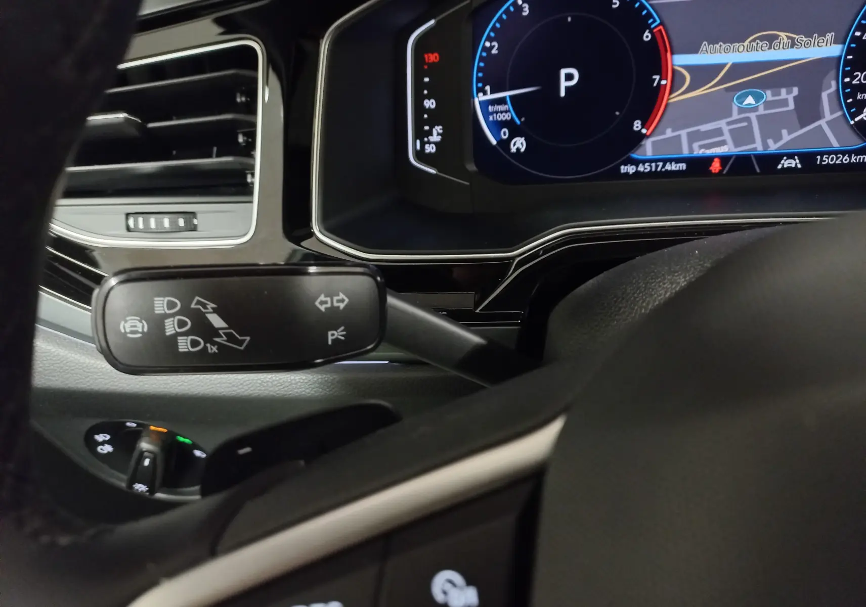 Vue rapprochée du combiné d'instruments et du commodo gauche du Volkswagen Taigo blanc, avec affichage numérique et commandes au volant.