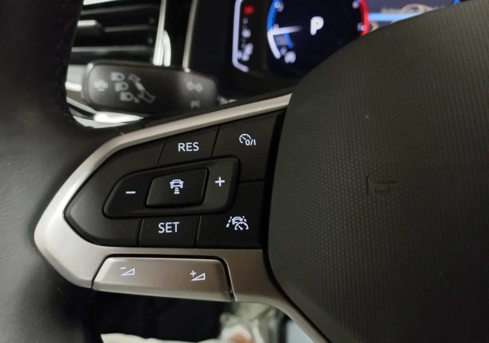 Gros plan sur les commandes au volant côté gauche du Volkswagen Taigo 2025, finition R-Line avec régulateur adaptatif.