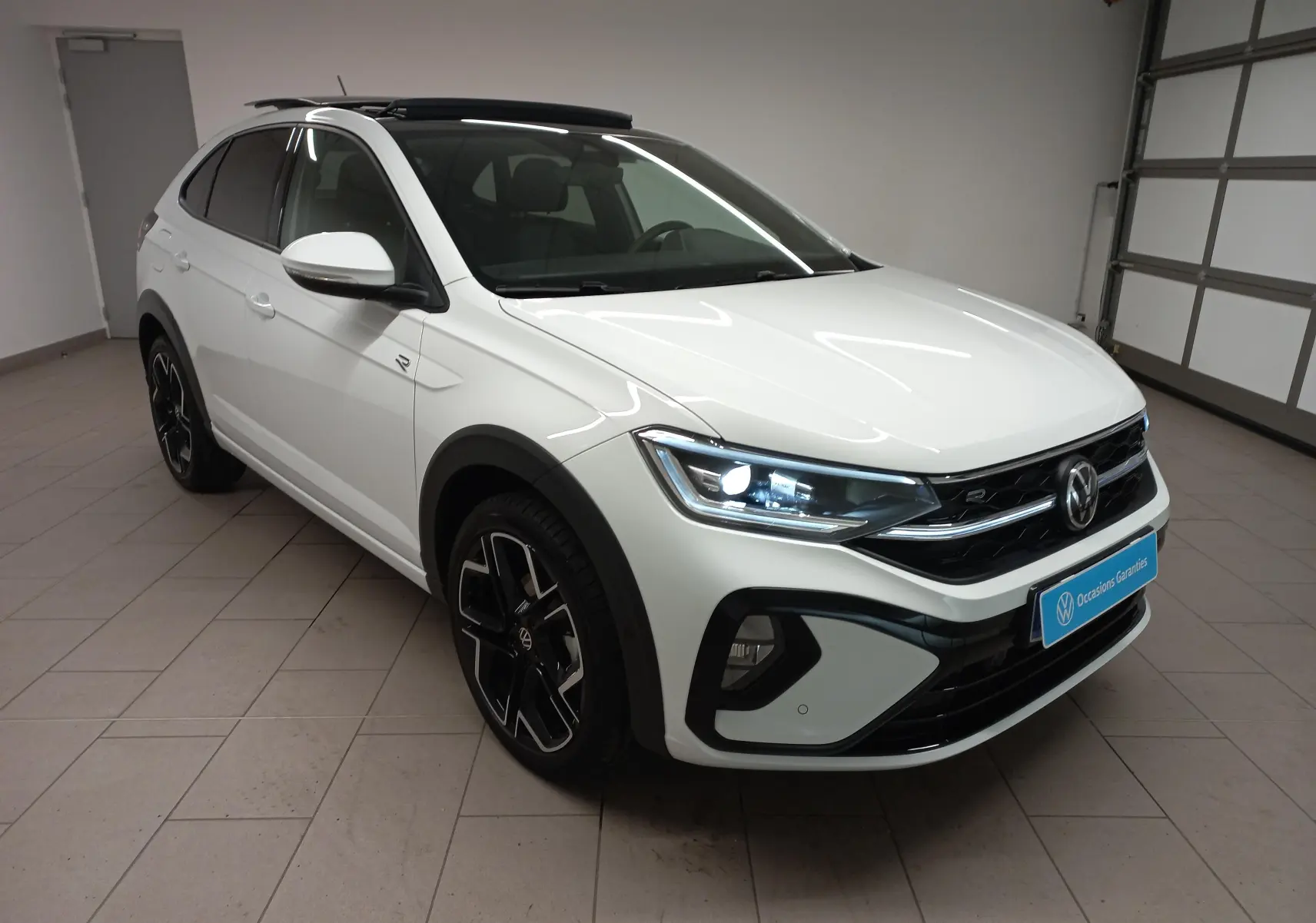 Volkswagen Taigo blanc pur 2025 en 3/4 avant droit, version R-Line avec toit ouvrant et jantes noires distinctives.