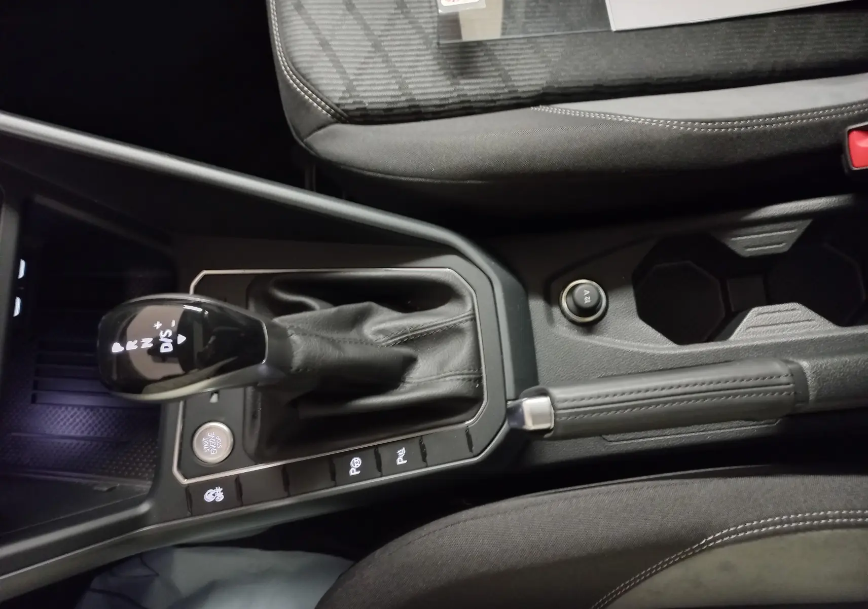 Vue rapprochée de la console centrale du Volkswagen Taigo blanc pur 2025, avec levier de vitesse automatique et frein à main.