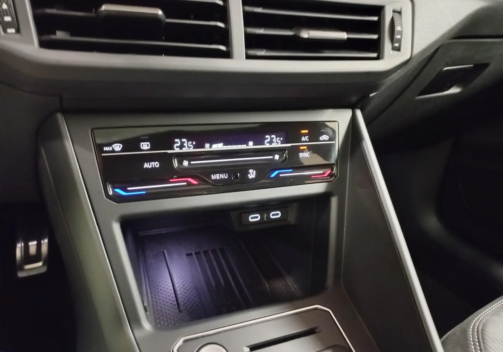 Vue rapprochée de la console centrale du Volkswagen Taigo blanc, avec commandes climatisation digitale et ports USB visibles.