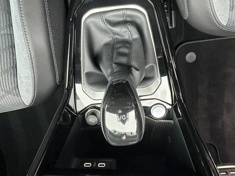 Vue plongeante sur la commande de boîte automatique noire du Volkswagen T-Roc gris, avec sellerie tissu et alcantara visible.