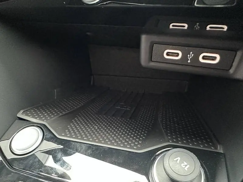 Gros plan sur la console centrale du Volkswagen T-Roc 2025, montrant les ports USB et prise 12V noirs.