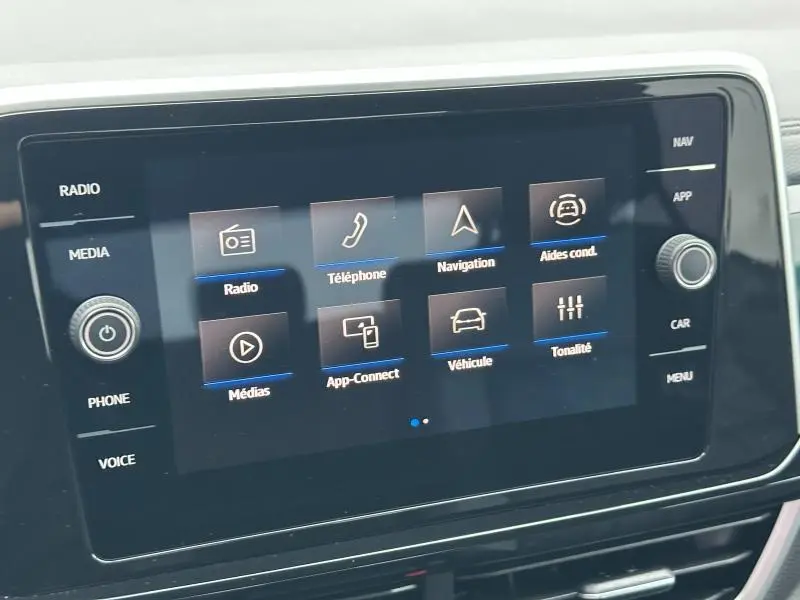 Écran tactile central du Volkswagen T-Roc 2025 affichant les options radio, téléphone, navigation et aides à la conduite.