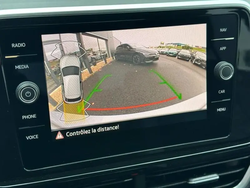 Écran tactile montrant la caméra de recul du Volkswagen T-Roc gris en vue arrière avec guidage de trajectoire verte et rouge.