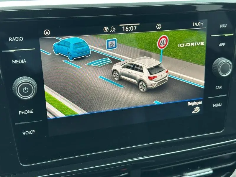 Affichage écran tactile montrant une Volkswagen T-Roc grise vue en 3/4 arrière droite avec signalisation 60 km/h.