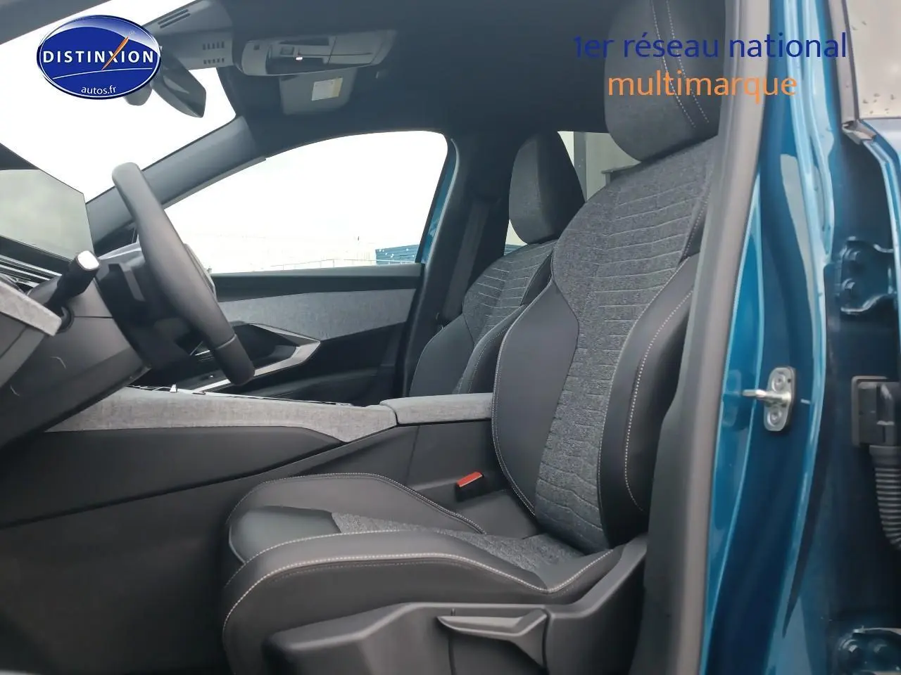 Intérieur du Peugeot 3008 bleu 2025 vu côté conducteur, montrant les sièges en tissu et cuir avec console centrale grise.