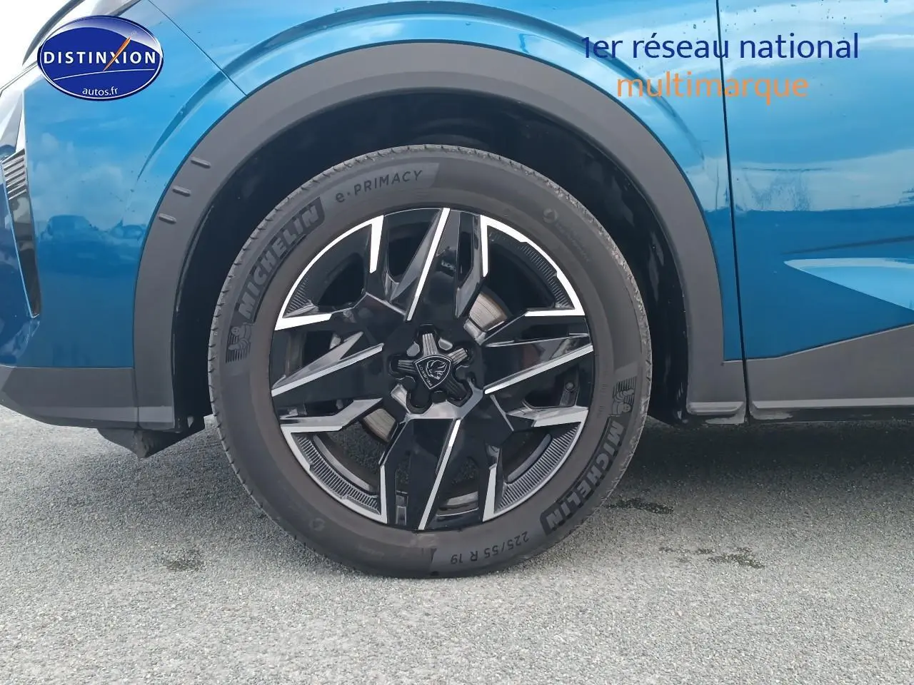 Gros plan sur la roue avant gauche avec jante alu noire et argentée du Peugeot 3008 bleu 2025.
