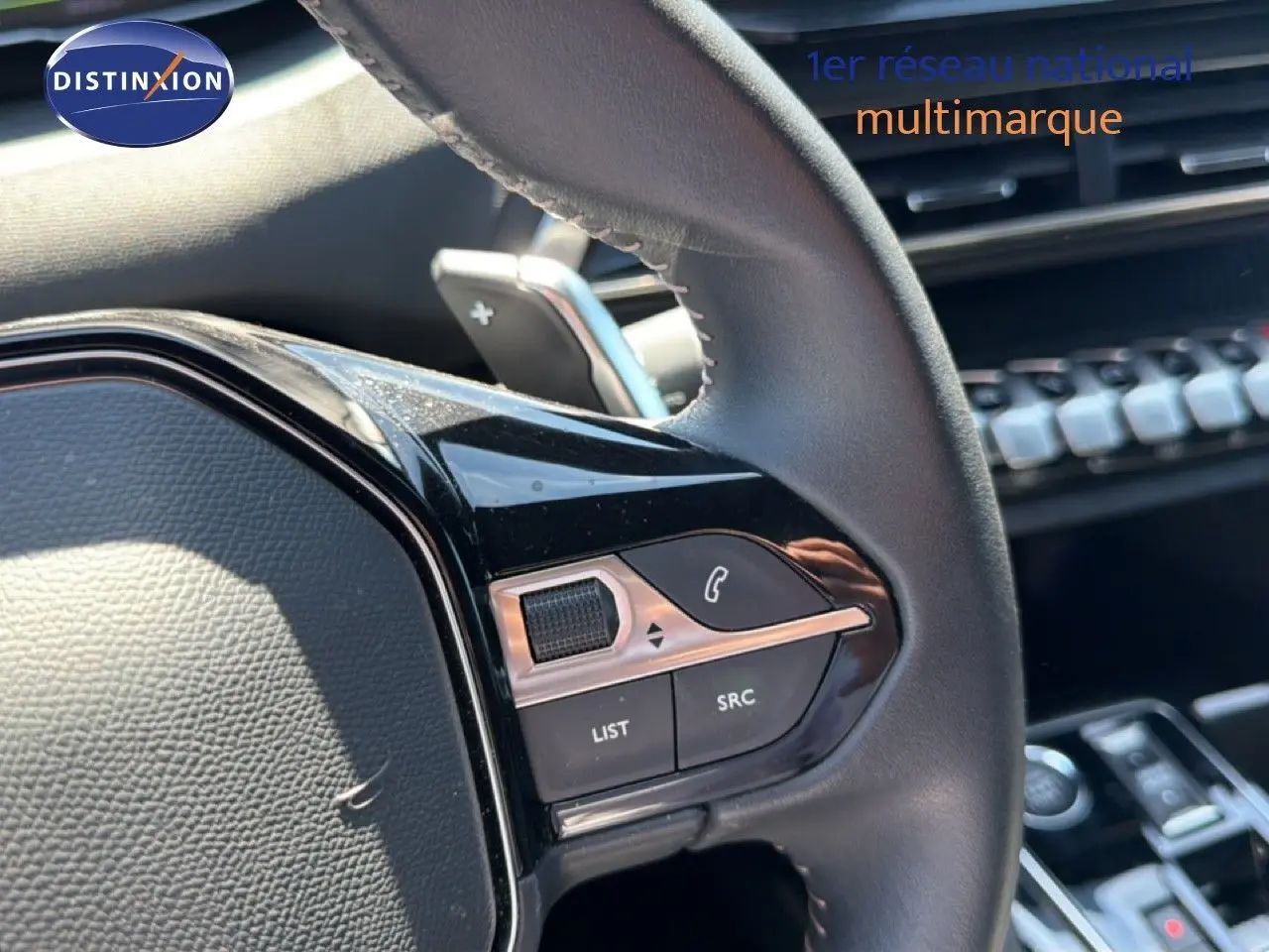 Gros plan sur le volant côté gauche du Peugeot 3008 Hybrid gris, avec commandes intégrées et palettes au volant visibles.