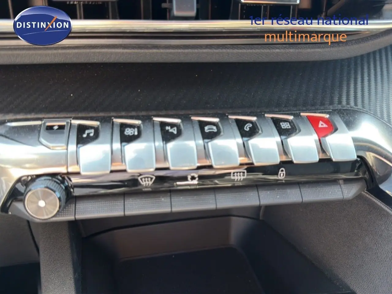 Gros plan sur la rangée de boutons métalliques du tableau de bord du Peugeot 3008 gris Artense, version hybride 2024.