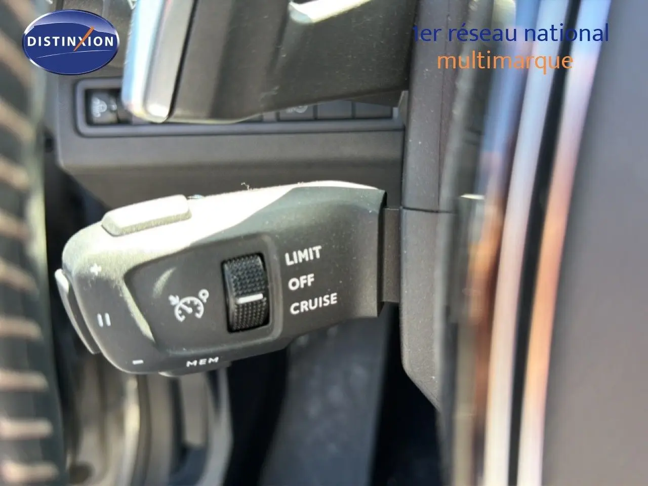 Gros plan sur la commande de régulateur de vitesse à gauche du volant d’un Peugeot 3008 gris Artense 2024.