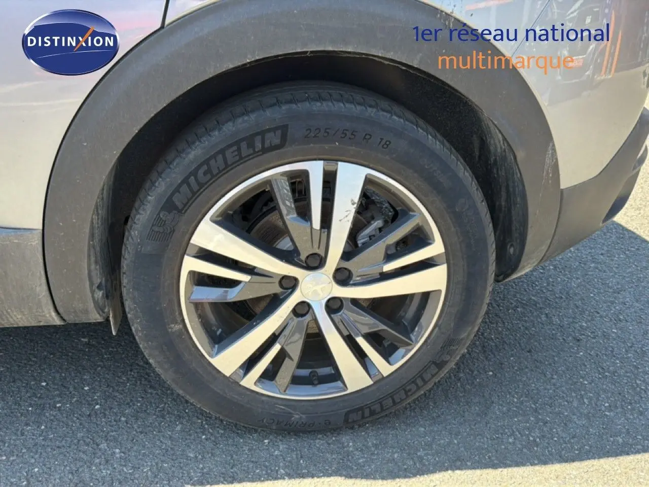 Gros plan sur la roue avant gauche du Peugeot 3008 Hybrid gris Artense métal avec jante alliage bicolore.