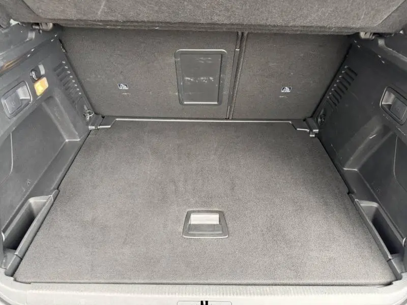 Vue intérieure du coffre spacieux et propre du Peugeot 3008 2024 en Gris Platinium, avec compartiments latéraux et trappe centrale.