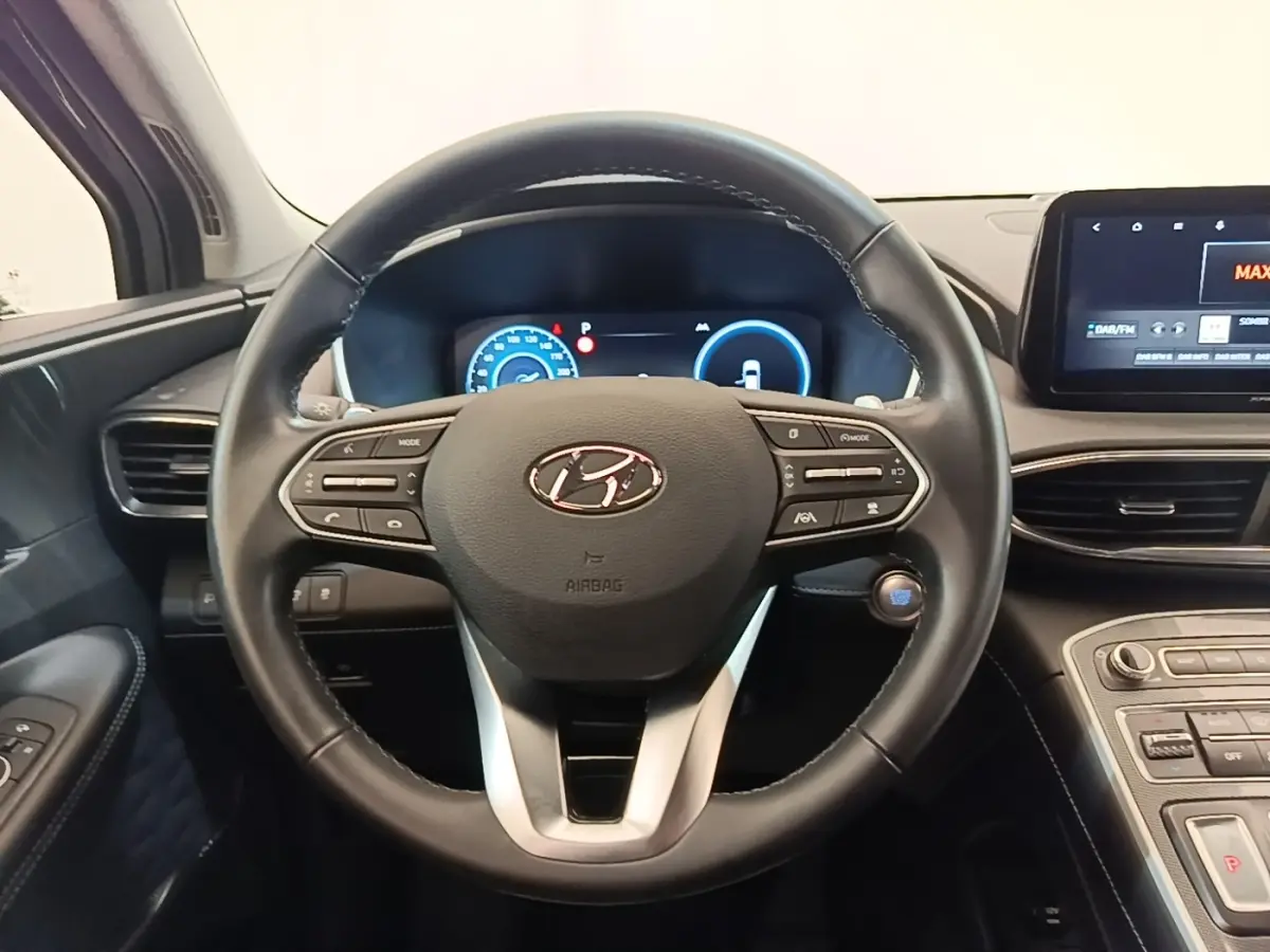 Vue intérieure centrée sur le volant cuir noir du Hyundai Santa Fe 2023 avec tableau de bord digital et écran tactile.