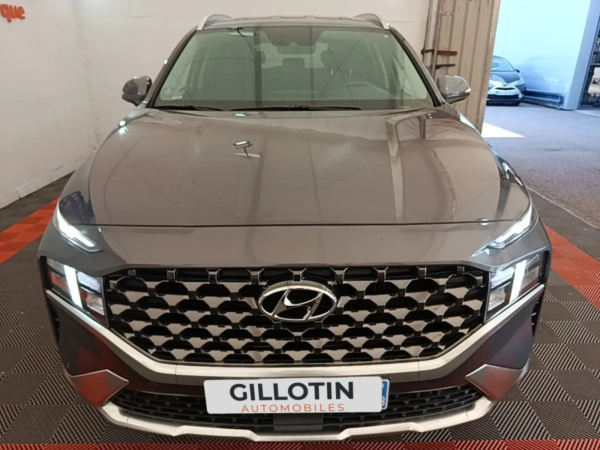 Vue avant d’un Hyundai Santa Fe gris foncé 2023 avec calandre imposante et phares LED allumés en intérieur.