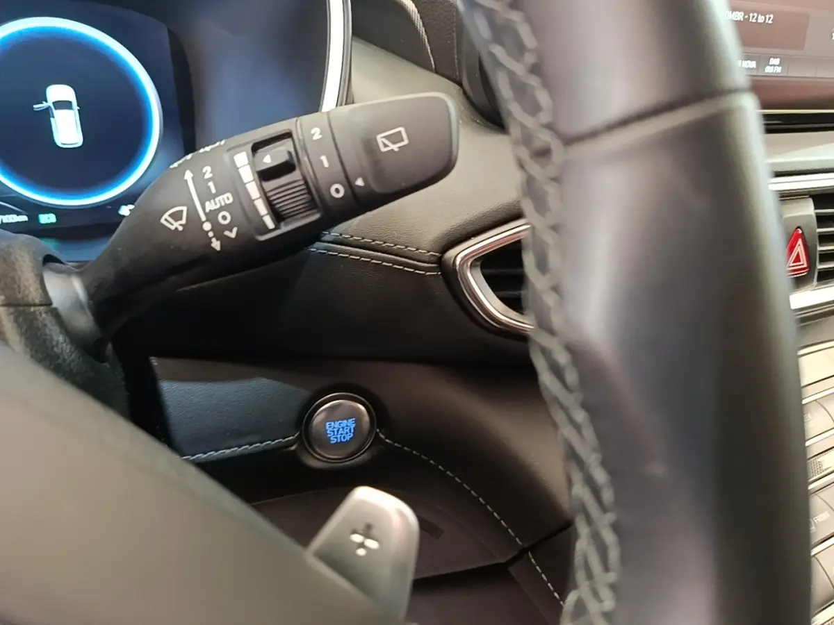 Gros plan sur le bouton start/stop et la commande d’essuie-glace, volant cuir partiellement visible, intérieur noir du Hyundai Santa Fe.