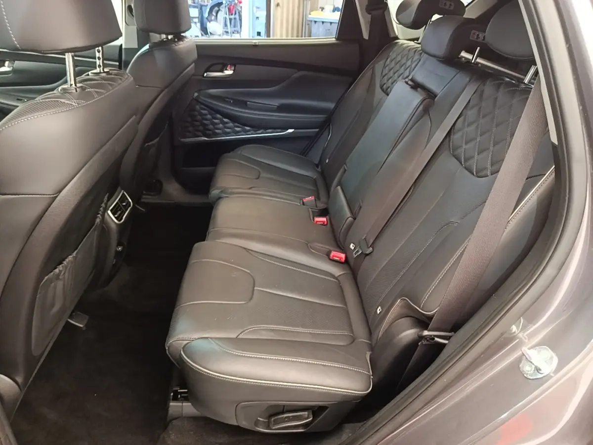 Vue intérieure côté droit des sièges arrière en cuir noir du Hyundai Santa Fe 2023 gris foncé, avec surpiqûres et ceintures visibles.