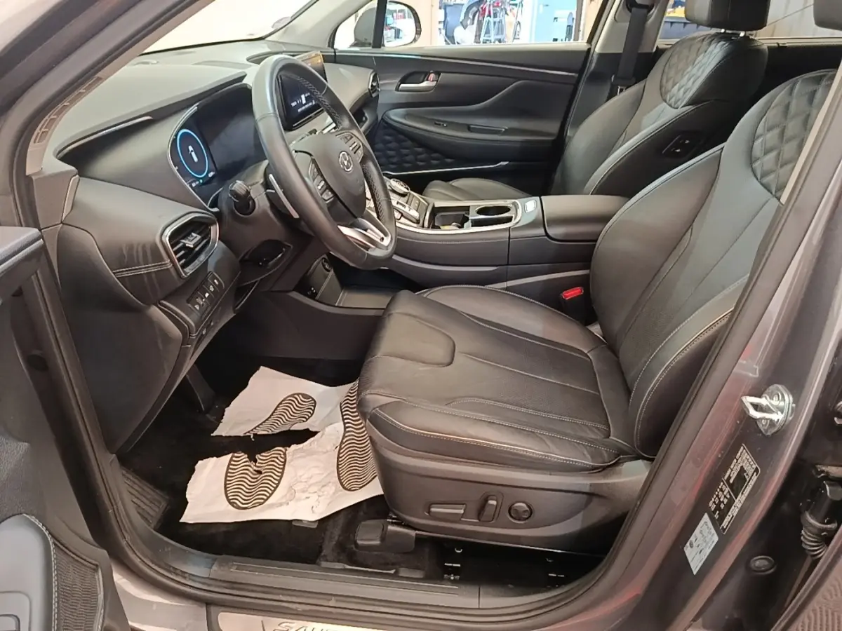Vue intérieure côté conducteur du Hyundai Santa Fe 2023 gris foncé, sièges cuir noirs et tableau de bord moderne.