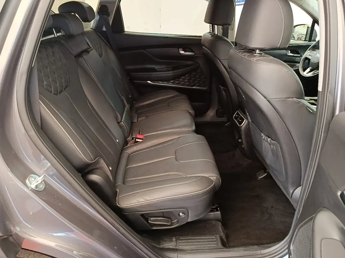 Vue intérieure côté gauche des sièges arrière en cuir noir du Hyundai Santa Fe 2023 gris foncé, avec détails couture apparents.