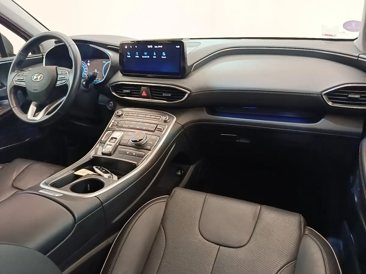 Vue intérieure côté passager du Hyundai Santa Fe 2023, tableau de bord noir avec écran tactile central et volant cuir.