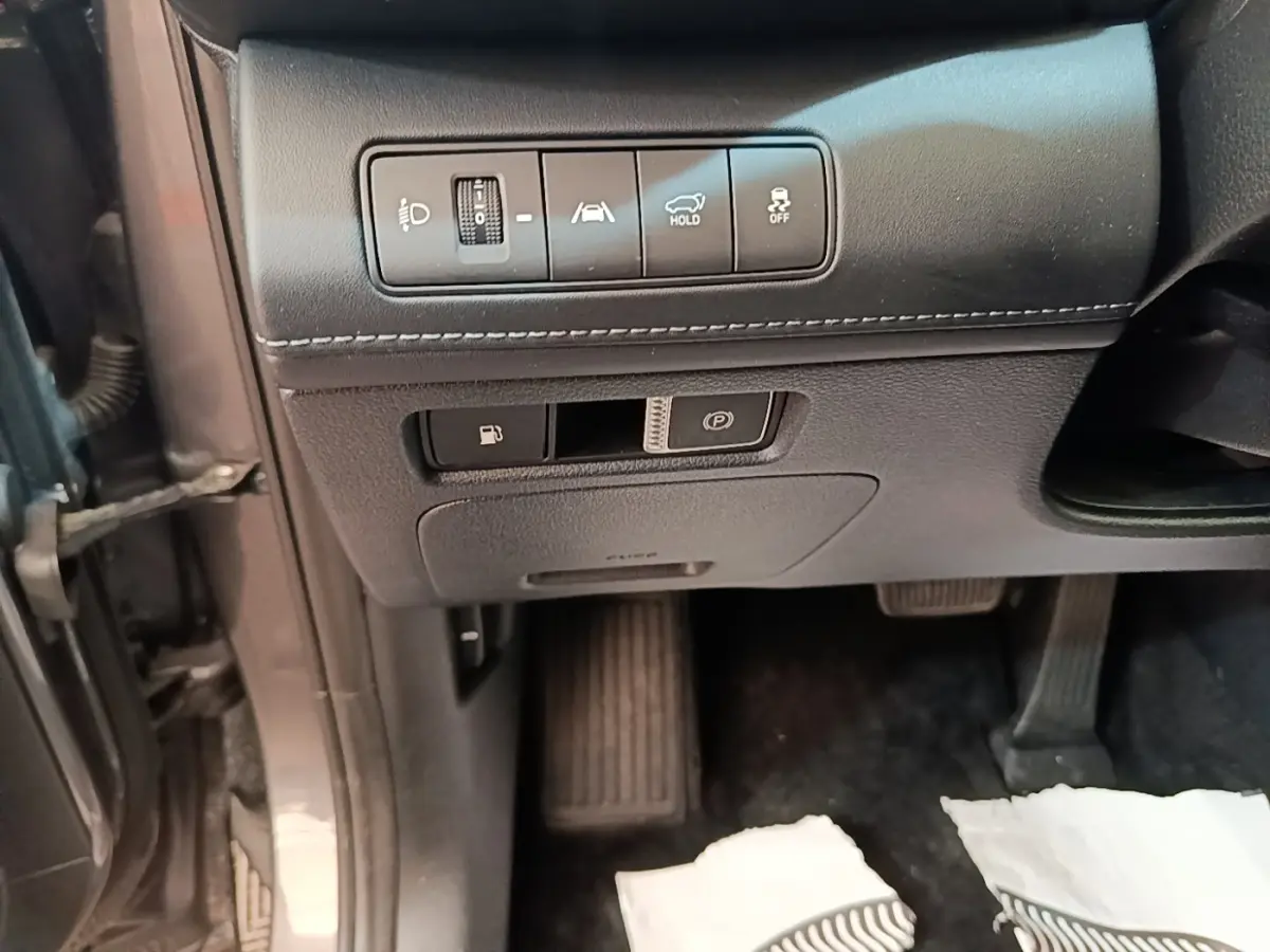 Détail intérieur côté conducteur du Hyundai Santa Fe gris foncé montrant les commandes d’aide à la conduite et frein de parking électrique.