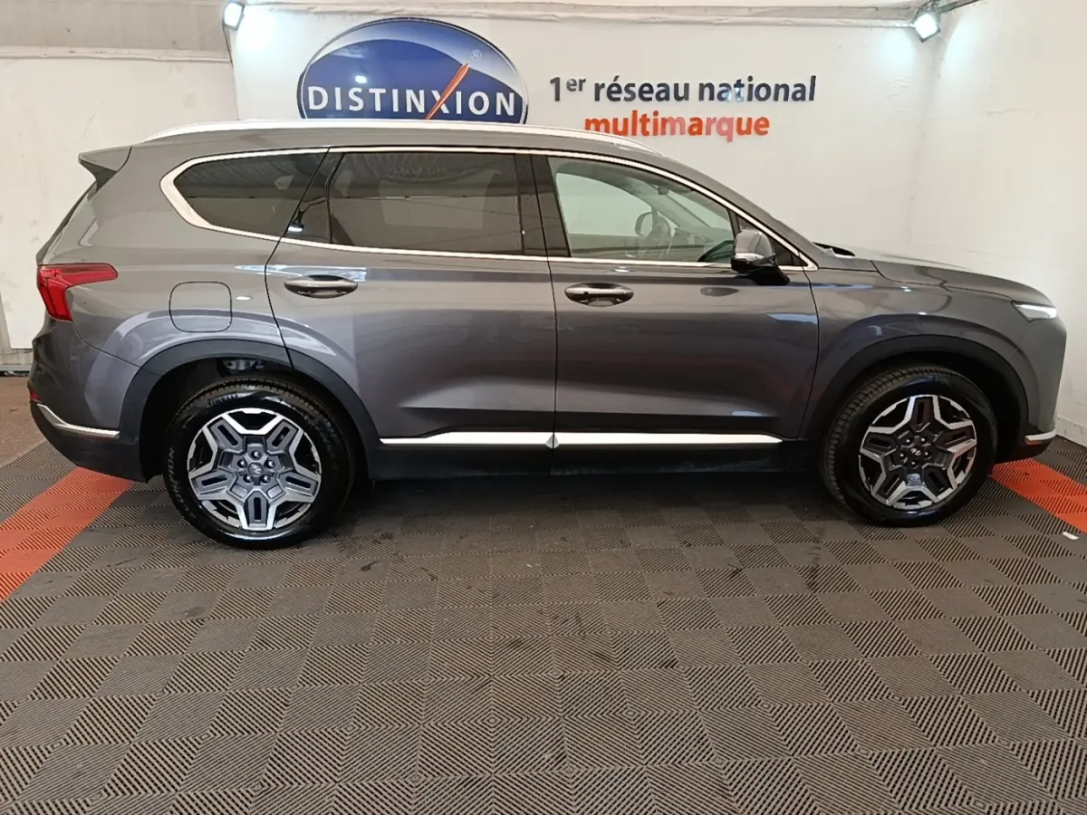 Vue latérale droite du Hyundai Santa Fe gris foncé 2023 avec jantes alliage et lignes chromées sur les portières.