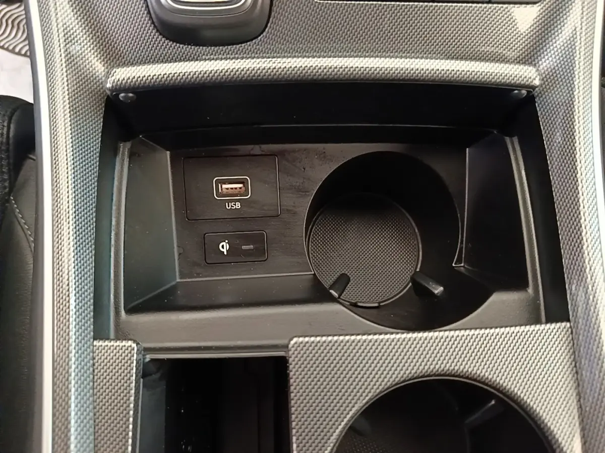 Gros plan sur la console centrale du Hyundai Santa Fe 2023, avec port USB, chargeur à induction et porte-gobelet.