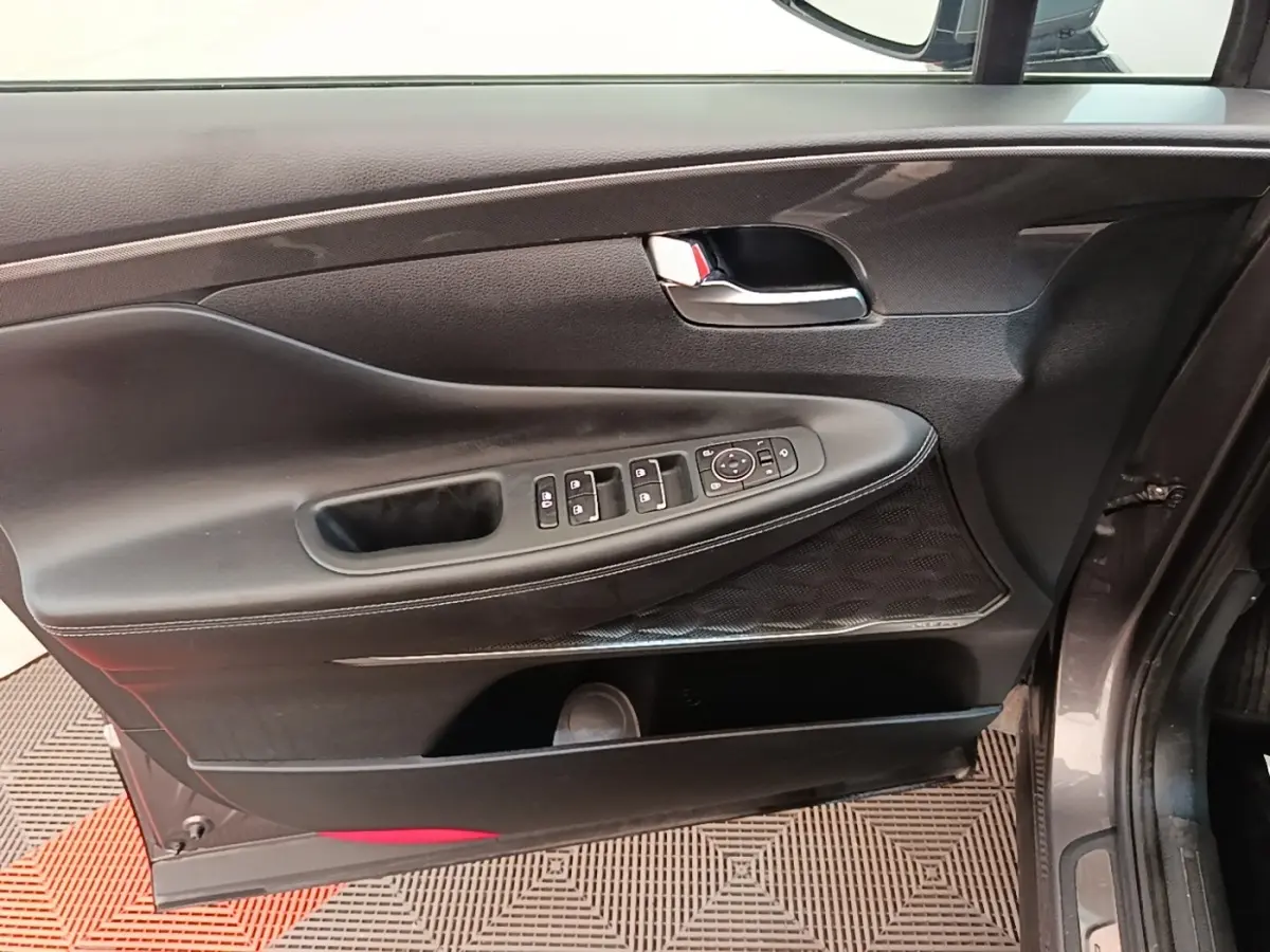 Vue intérieure de la porte avant gauche du Hyundai Santa Fe gris foncé, avec commandes électriques et poignée chromée.