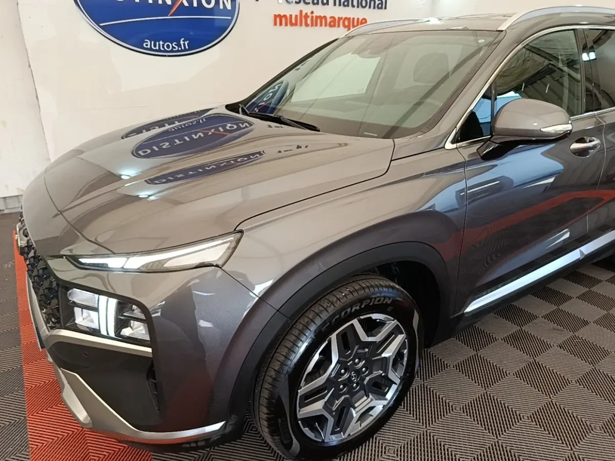 Vue 3/4 avant droit du Hyundai Santa Fe gris foncé 2023 avec jantes alliage et feux LED distinctifs.