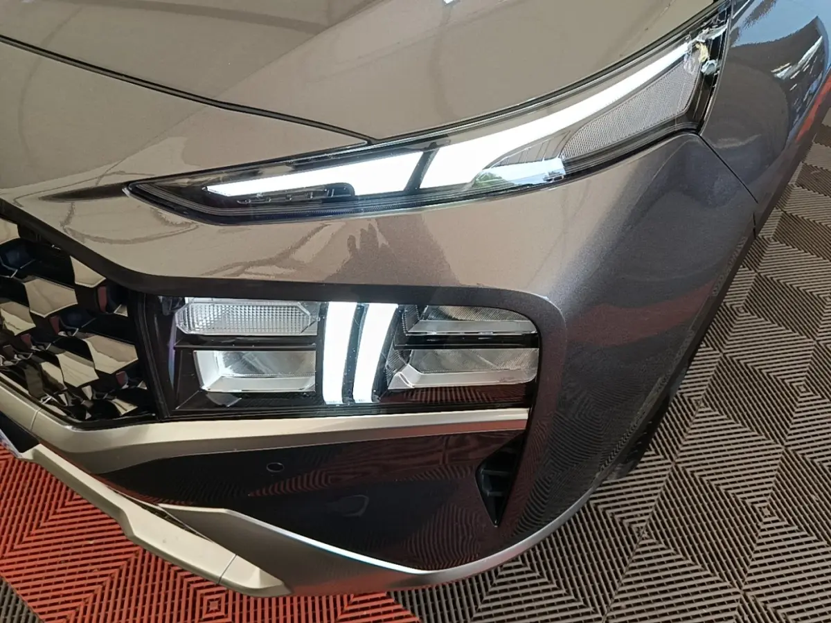 Gros plan sur l'avant droit gris foncé du Hyundai Santa Fe 2023, mettant en valeur ses phares LED et sa calandre distinctive.