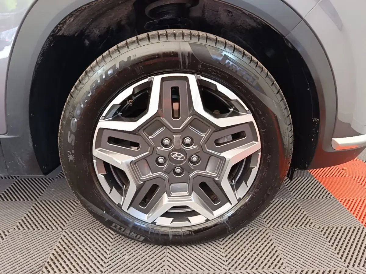 Gros plan sur la roue avant droite du Hyundai Santa Fe gris foncé, jante acier au design étoilé, pneu Pirelli Scorpion.