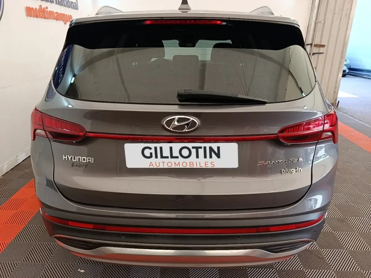 Vue arrière d’un Hyundai Santa Fe gris foncé hybride rechargeable avec feux LED et logo plug-in visibles.