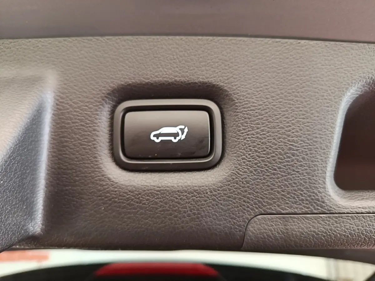 Bouton noir d'ouverture électrique du coffre sur panneau intérieur gris texturé du Hyundai Santa Fe 2023.