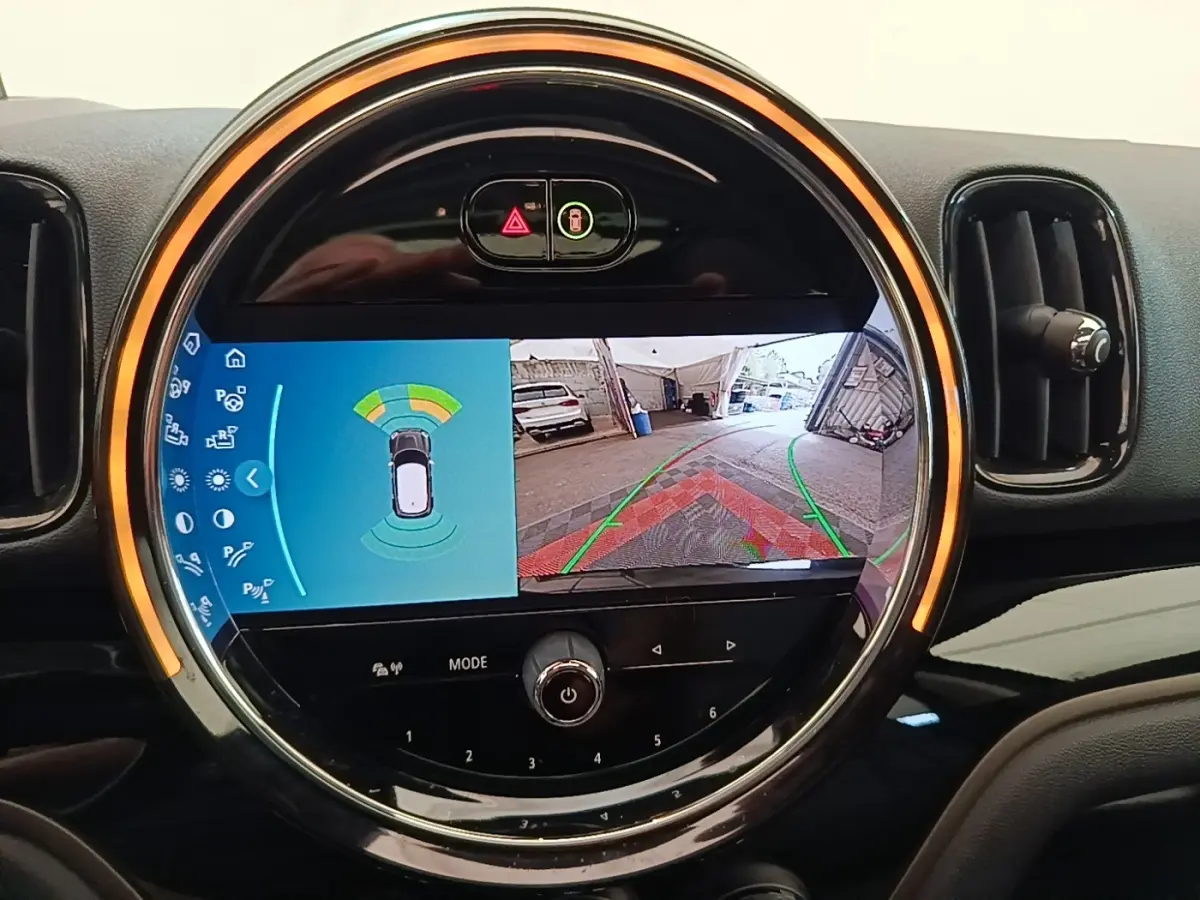 Vue rapprochée de l'écran tactile central rond du MINI Countryman 2023 affichant la caméra de recul et les capteurs de stationnement.